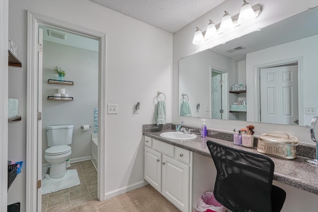 bathroom featuring toilet, vanity, tile patterned floors, a tub, and a textured ceiling