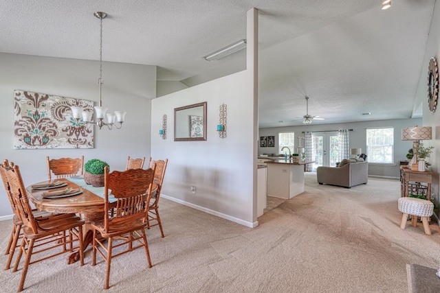 carpeted dining room with a textured ceiling, vaulted ceiling, french doors, and ceiling fan with notable chandelier