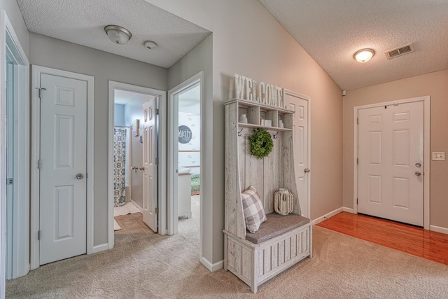 foyer with vaulted ceiling, carpet, and a textured ceiling