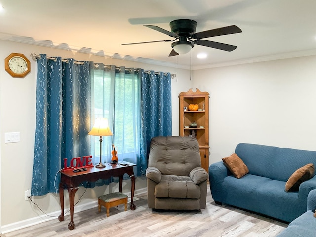 living area featuring a ceiling fan, crown molding, baseboards, and wood finished floors