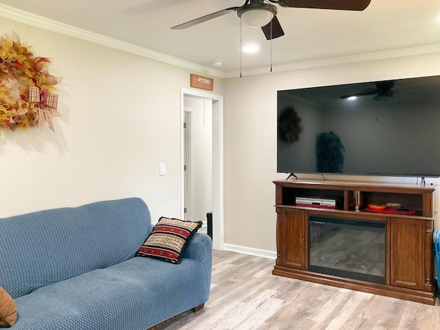 living room featuring baseboards, a ceiling fan, a glass covered fireplace, wood finished floors, and crown molding