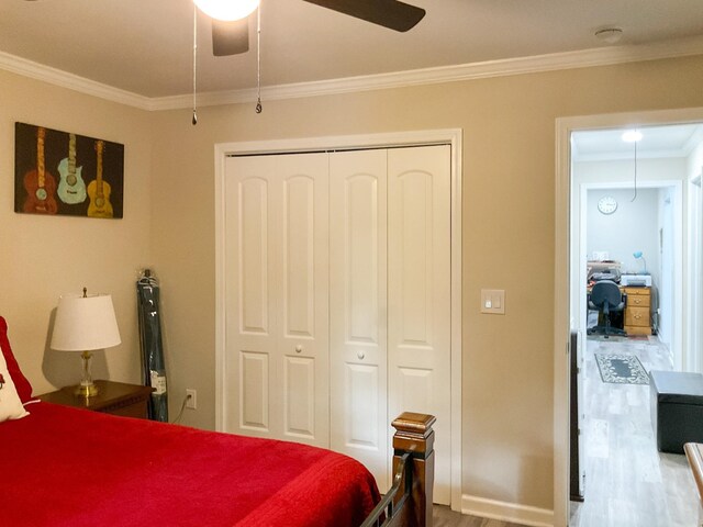 bedroom featuring ceiling fan, crown molding, wood-type flooring, and a closet