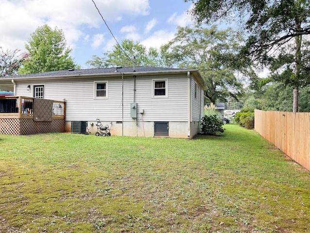 rear view of house featuring a lawn, central AC unit, crawl space, fence, and a wooden deck