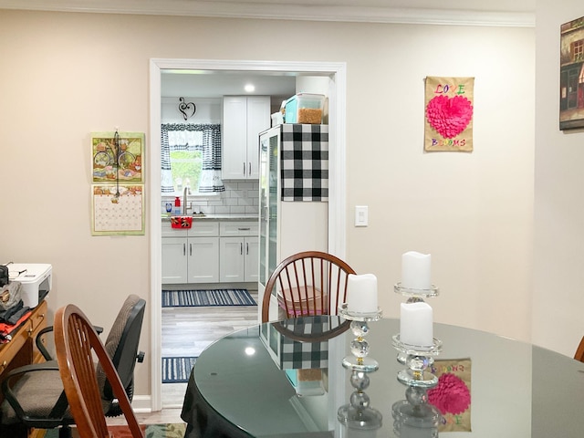 dining space featuring light wood finished floors and ornamental molding