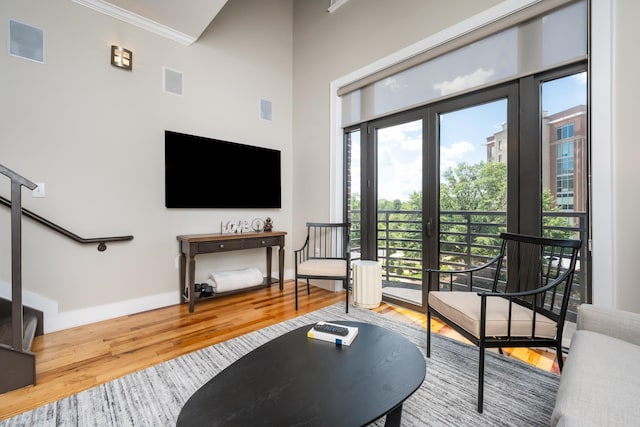 living room with crown molding, french doors, hardwood / wood-style flooring, and a towering ceiling