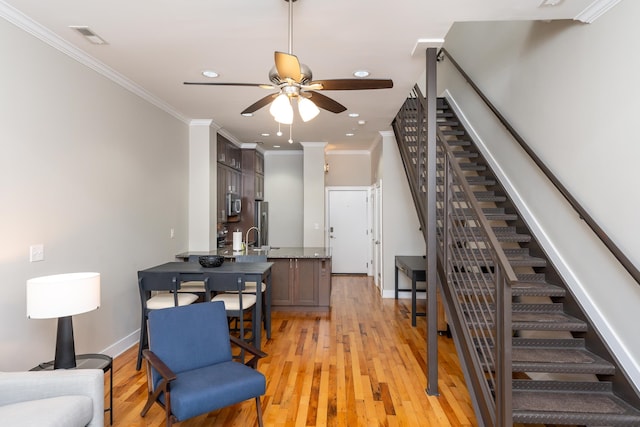 living room with ceiling fan, sink, light hardwood / wood-style floors, and ornamental molding