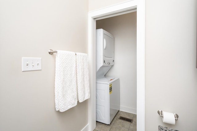 laundry room with stacked washing maching and dryer and light tile patterned floors