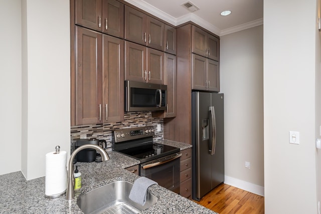 kitchen featuring backsplash, sink, appliances with stainless steel finishes, light stone counters, and light hardwood / wood-style floors