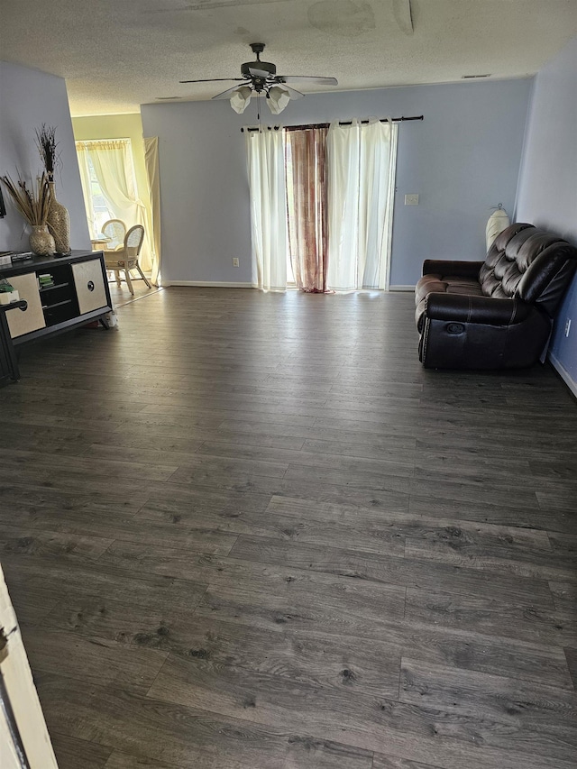 living area with ceiling fan, baseboards, dark wood finished floors, and a textured ceiling