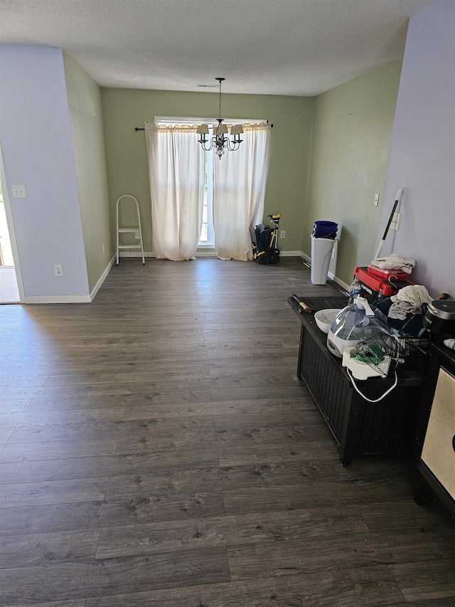 dining room featuring an inviting chandelier, a textured ceiling, baseboards, and dark wood-type flooring