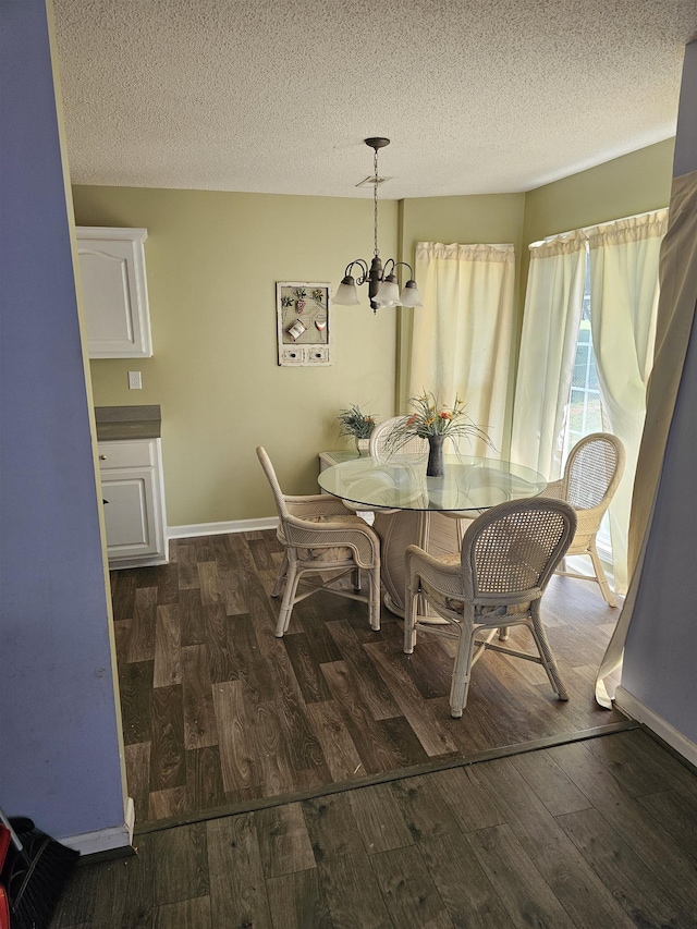 dining area with baseboards, a textured ceiling, wood finished floors, and a notable chandelier