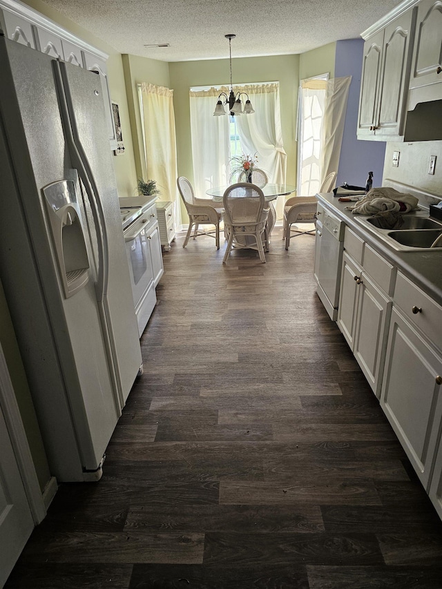 kitchen with a textured ceiling, electric range oven, white refrigerator with ice dispenser, dark wood-type flooring, and dishwasher