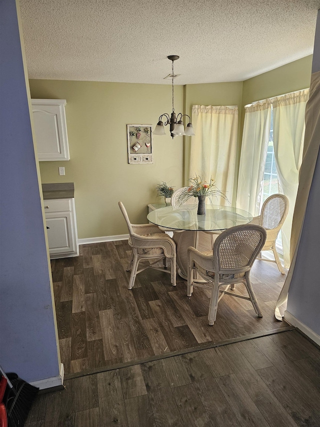 dining space featuring a notable chandelier, a textured ceiling, baseboards, and wood finished floors