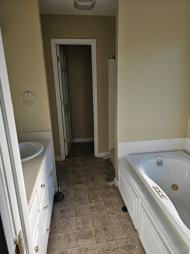 bathroom with a jetted tub, baseboards, visible vents, and vanity