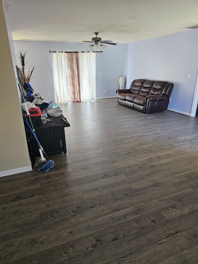 living area with a ceiling fan, dark wood-style flooring, a textured ceiling, and baseboards