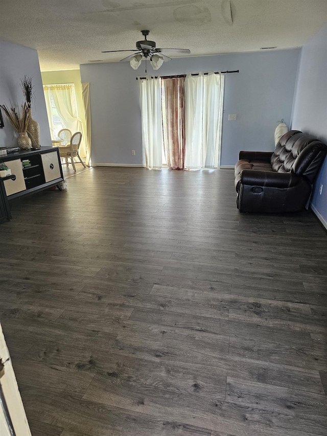 living area featuring a wealth of natural light, a ceiling fan, and dark wood-style flooring