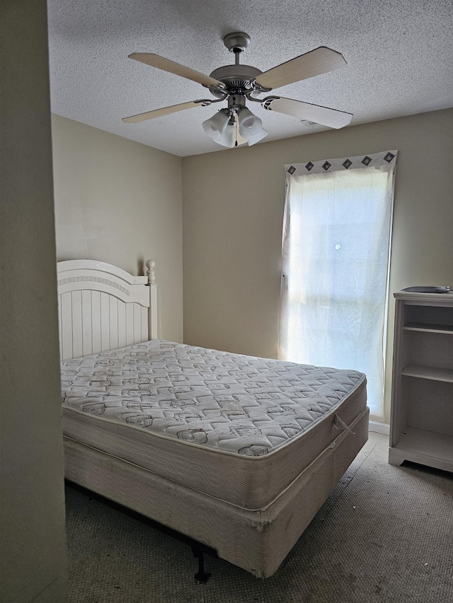 carpeted bedroom with ceiling fan and a textured ceiling