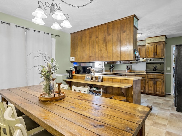 kitchen with pendant lighting, oven, a chandelier, refrigerator, and light tile patterned flooring