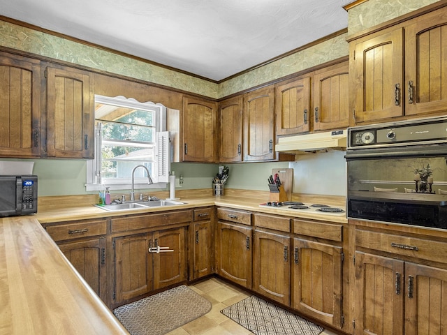 kitchen featuring premium range hood, light tile patterned floors, sink, black appliances, and crown molding