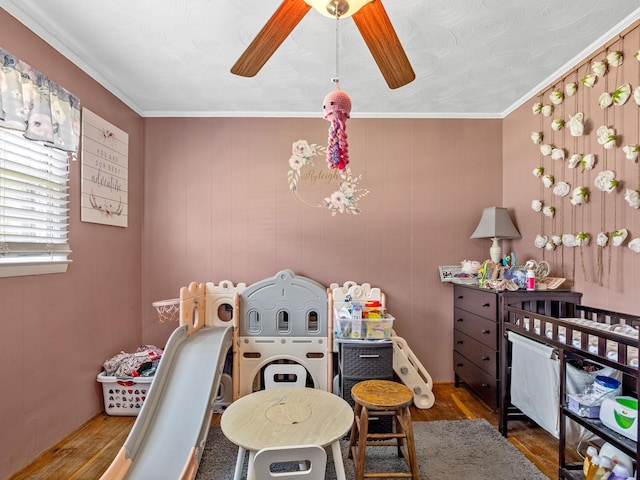 rec room featuring ceiling fan, ornamental molding, and wood-type flooring