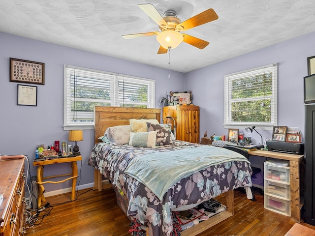 bedroom with ceiling fan, dark hardwood / wood-style flooring, and multiple windows