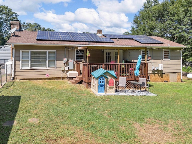 back of house with solar panels and a lawn