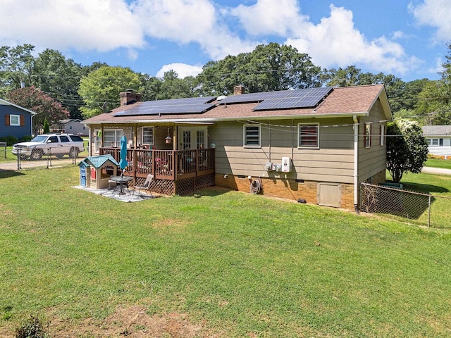 rear view of house with solar panels and a yard