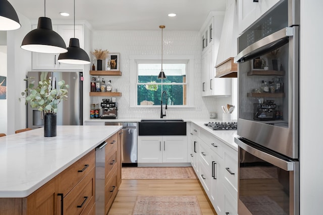 kitchen with a sink, white cabinetry, appliances with stainless steel finishes, light wood-type flooring, and open shelves