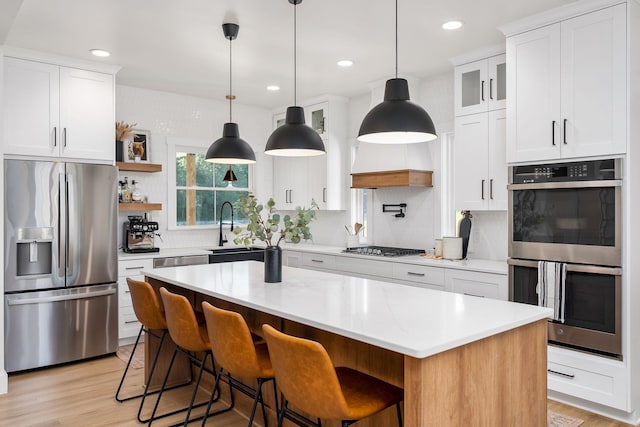 kitchen featuring stainless steel appliances, white cabinetry, a sink, and light wood-style flooring