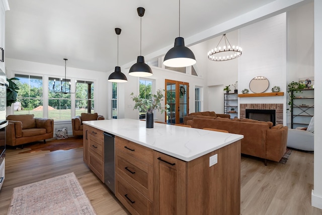 kitchen featuring a notable chandelier, a fireplace, open floor plan, brown cabinets, and light wood finished floors