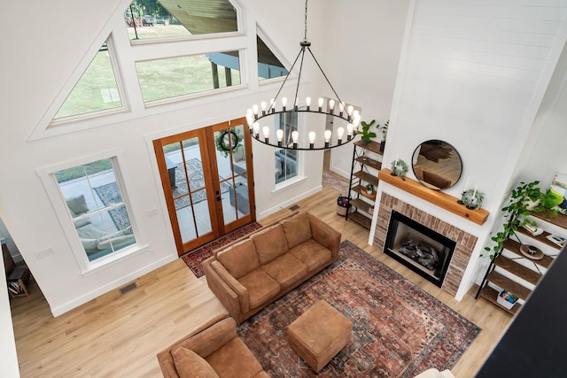 living room with a towering ceiling, a fireplace, a chandelier, and wood finished floors