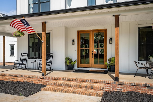 doorway to property with french doors, board and batten siding, and a porch