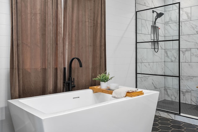 bathroom with a freestanding tub, walk in shower, and tile walls