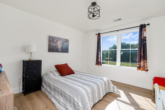 bedroom featuring visible vents, baseboards, and wood finished floors