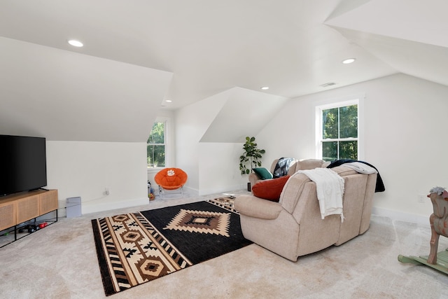 carpeted living area featuring a healthy amount of sunlight, vaulted ceiling, visible vents, and baseboards