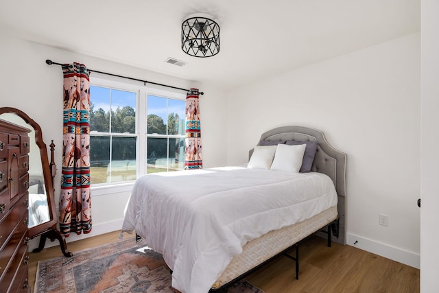 bedroom with visible vents, baseboards, and wood finished floors