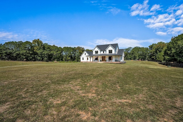 view of front of property with covered porch, a wooded view, and a front yard