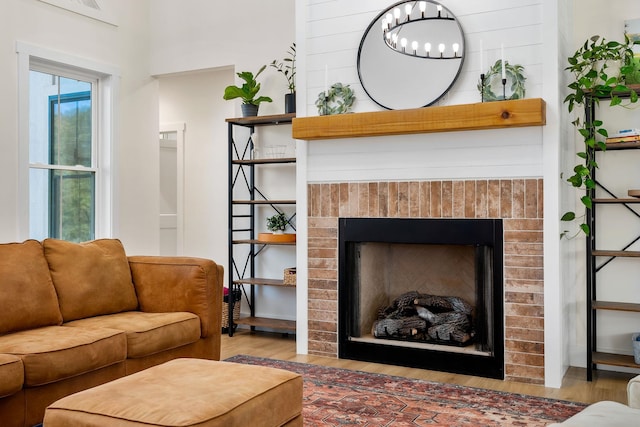 living room with a brick fireplace, a chandelier, and wood finished floors