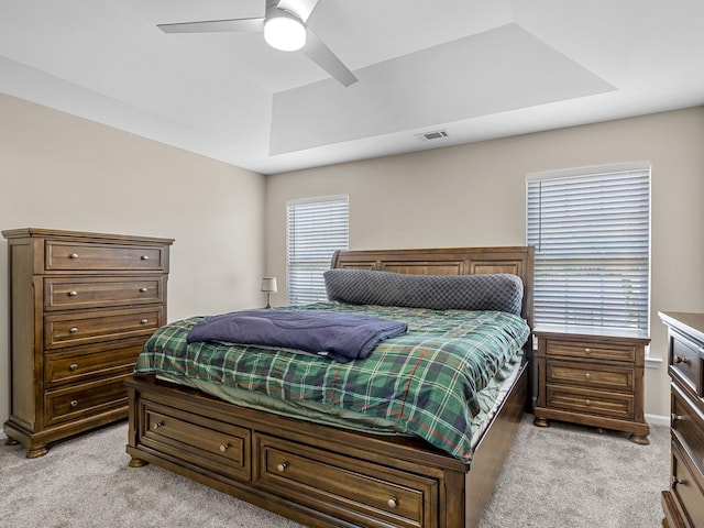 bedroom featuring ceiling fan, a raised ceiling, and light carpet