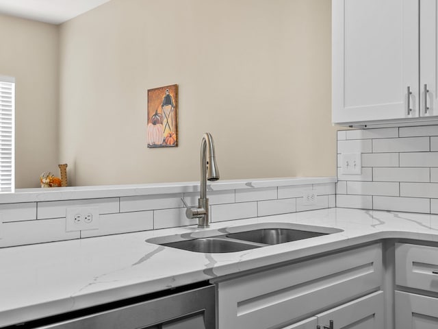 details with stainless steel dishwasher, light stone counters, sink, and tasteful backsplash