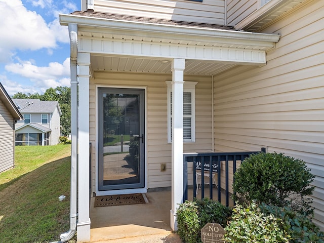 entrance to property featuring a lawn and covered porch