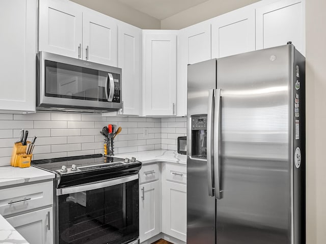 kitchen featuring white cabinets, appliances with stainless steel finishes, light stone countertops, and tasteful backsplash