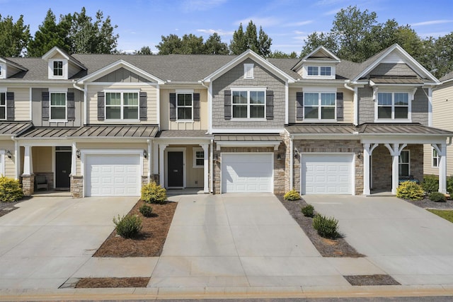 view of property featuring board and batten siding, a standing seam roof, a garage, stone siding, and driveway