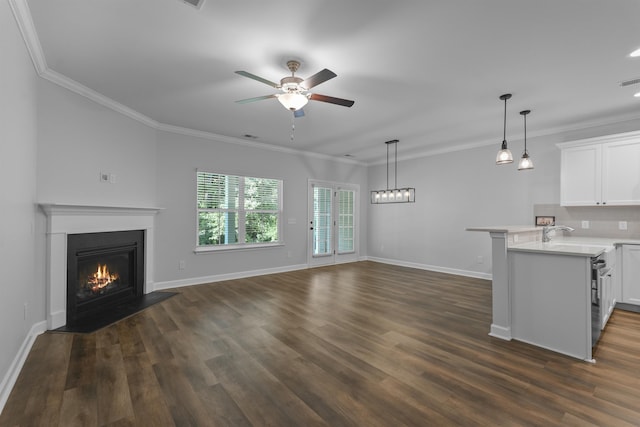 unfurnished living room featuring a warm lit fireplace, baseboards, a ceiling fan, dark wood-style floors, and ornamental molding