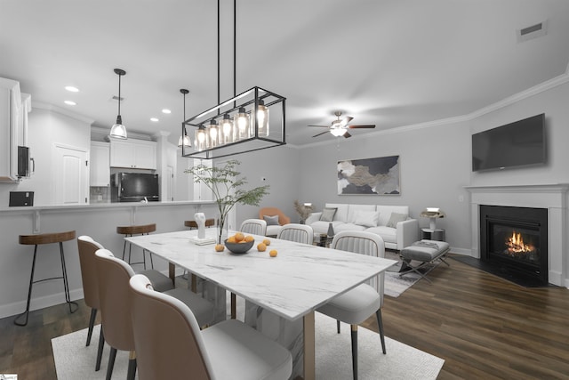 dining room featuring dark wood-style floors, a fireplace with flush hearth, visible vents, and crown molding