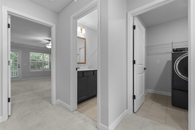 laundry area featuring light carpet, laundry area, washer / dryer, baseboards, and light tile patterned flooring