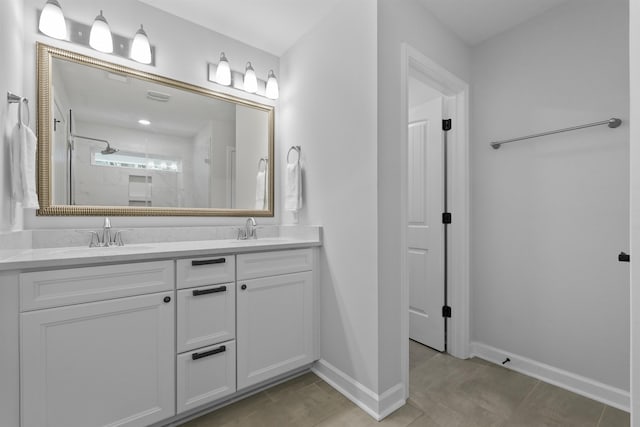 full bath with double vanity, baseboards, a sink, and tiled shower