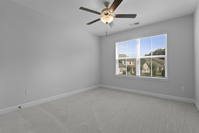 spare room with baseboards, visible vents, ceiling fan, and light colored carpet