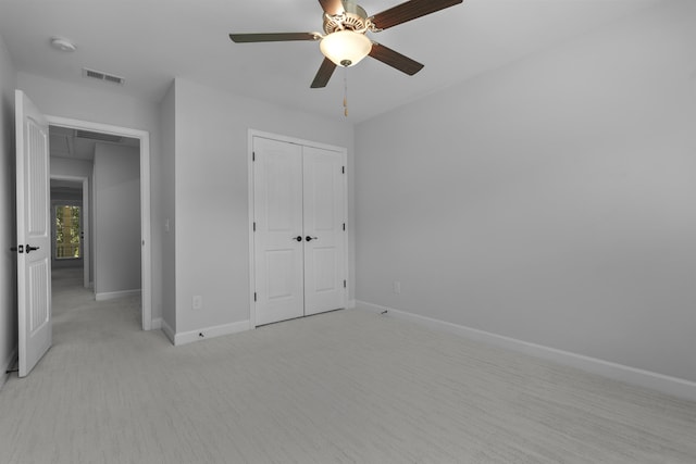 unfurnished bedroom with a closet, visible vents, attic access, light carpet, and baseboards