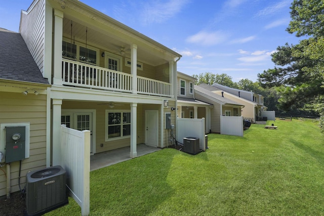 back of property featuring ceiling fan, a yard, a balcony, and central air condition unit